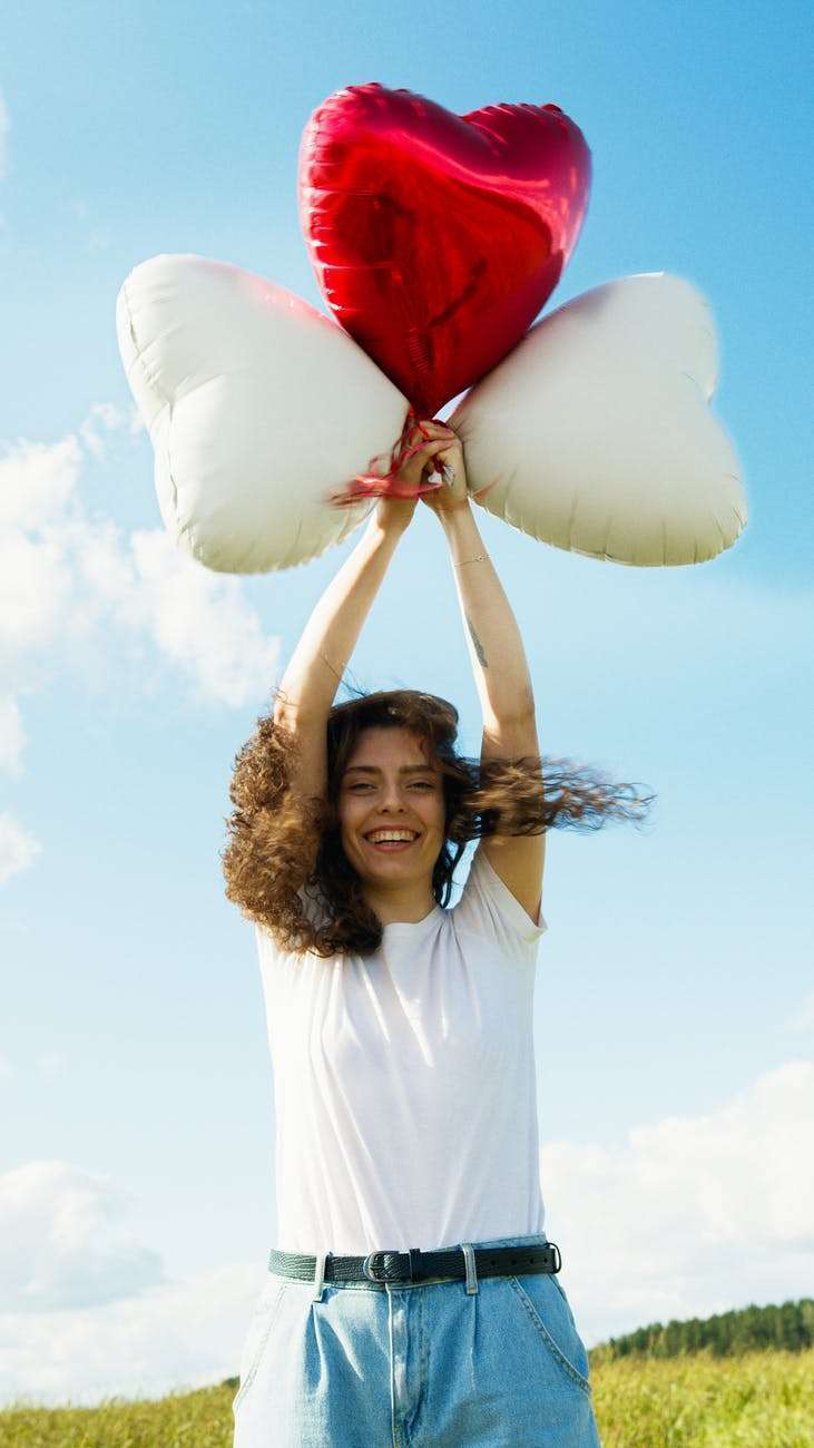 woman in white long sleeve shirt holding white and red balloons